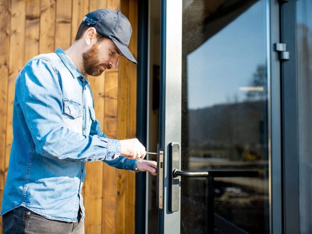 Locksmith adjusts a smart lock on a glass entry door