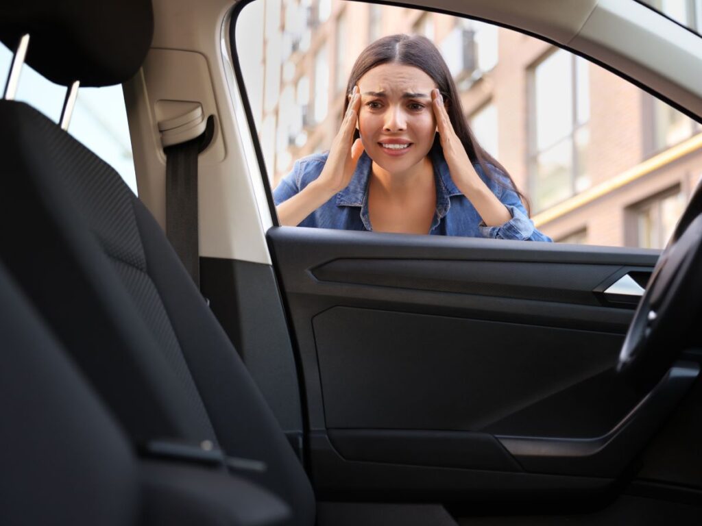 Stressed woman looking into car after realizing she’s locked out
