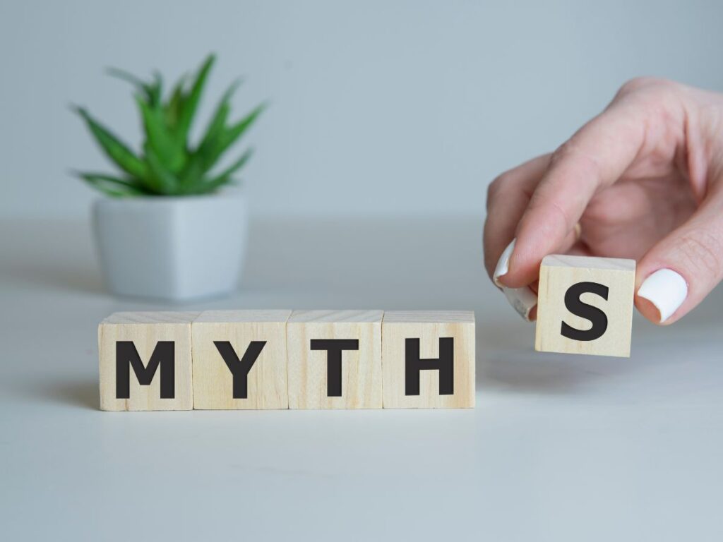 Wooden blocks spelling “MYTHS” with a hand placing the final letter