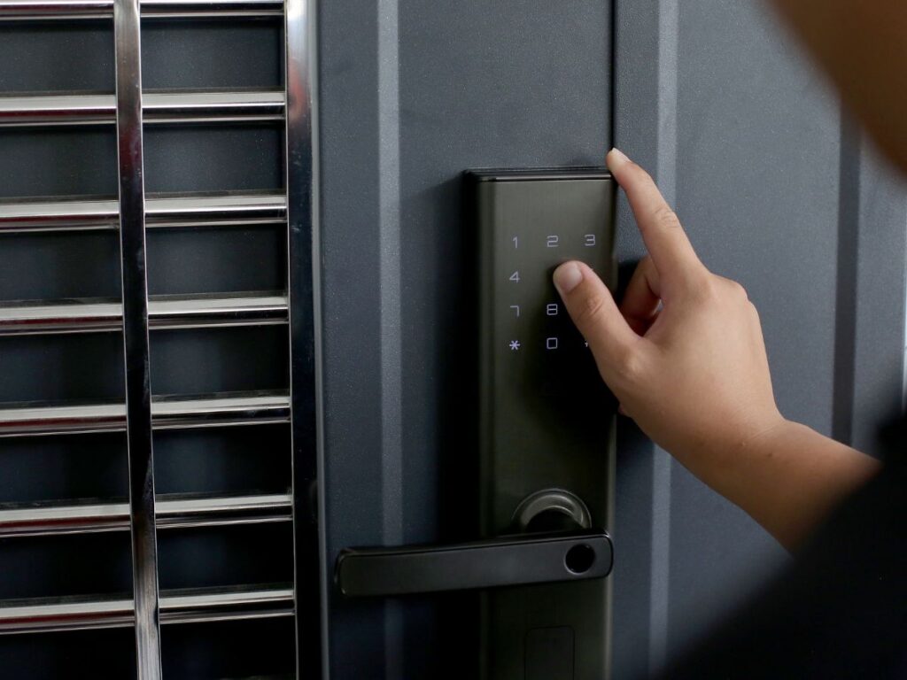 Hand using a keypad smart lock with handle on a gray security door