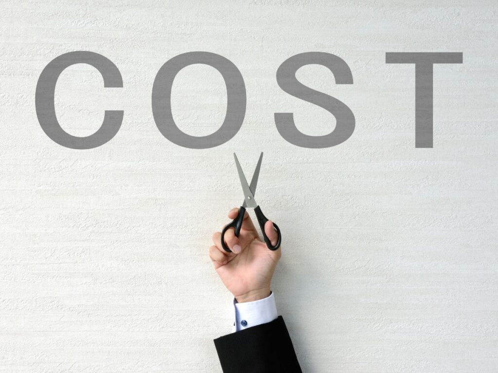 Hand holding scissors under the word COST