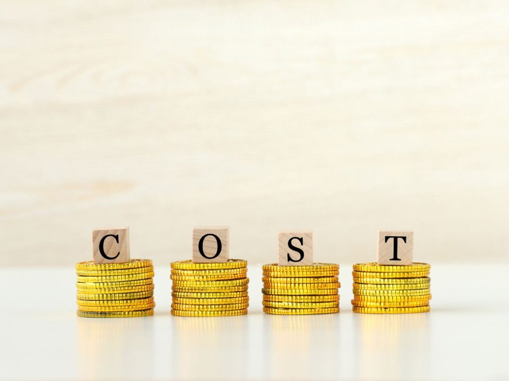 Wooden letters spelling COST on stacks of gold coins