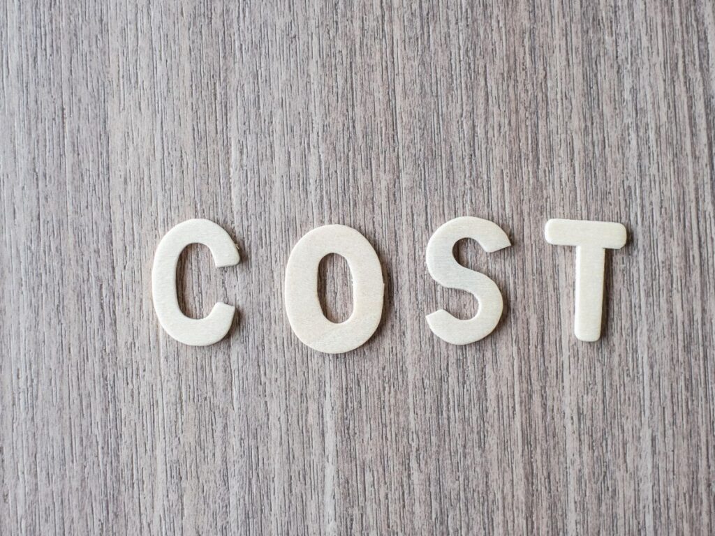 White wooden letters spelling COST on a gray wood background