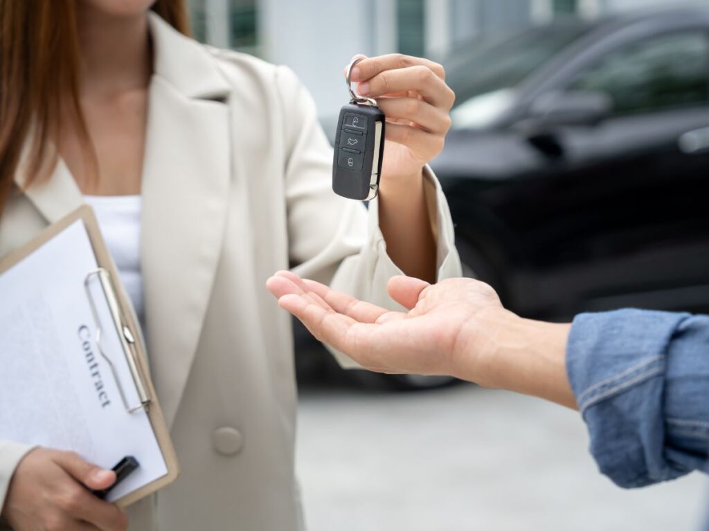 Person handing a car key fob to someone holding out a hand